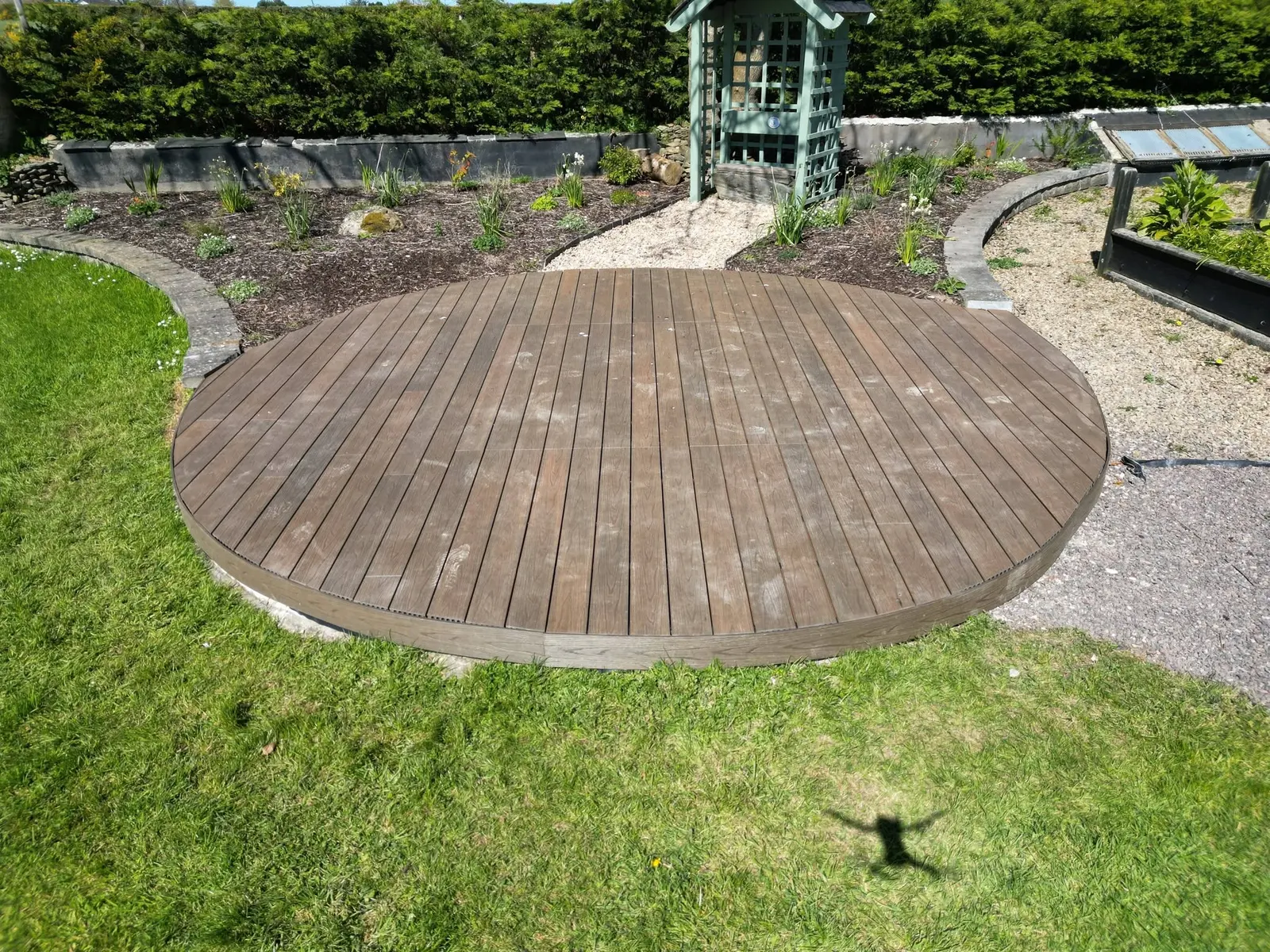 Rounded garden decking beside paths and planting