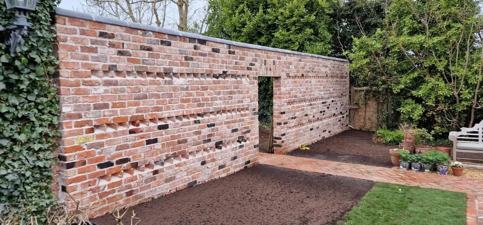 Brick garden wall beside a prepared planting area