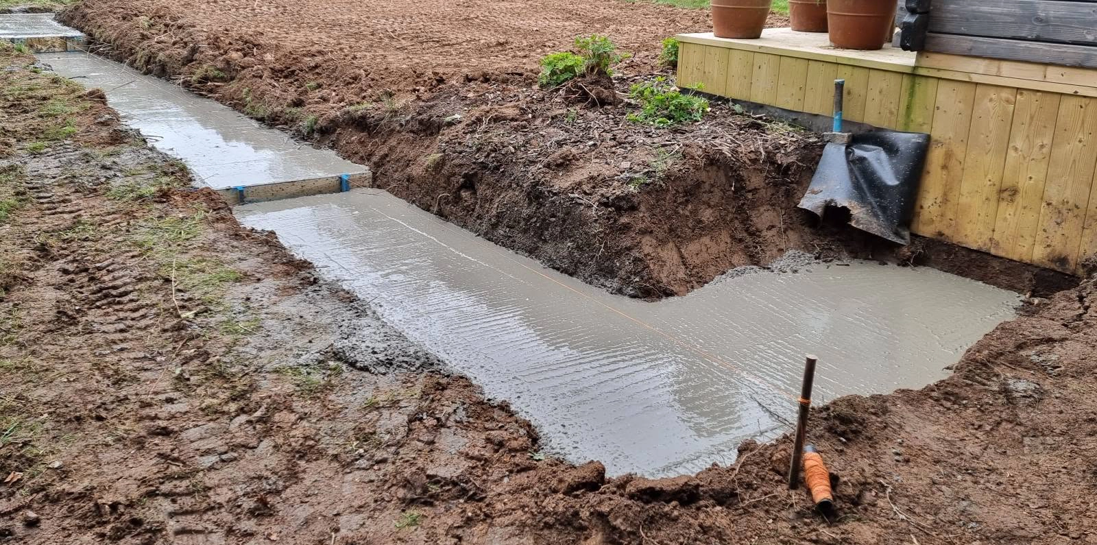 Excavated ground with a concrete strip beside the garden building