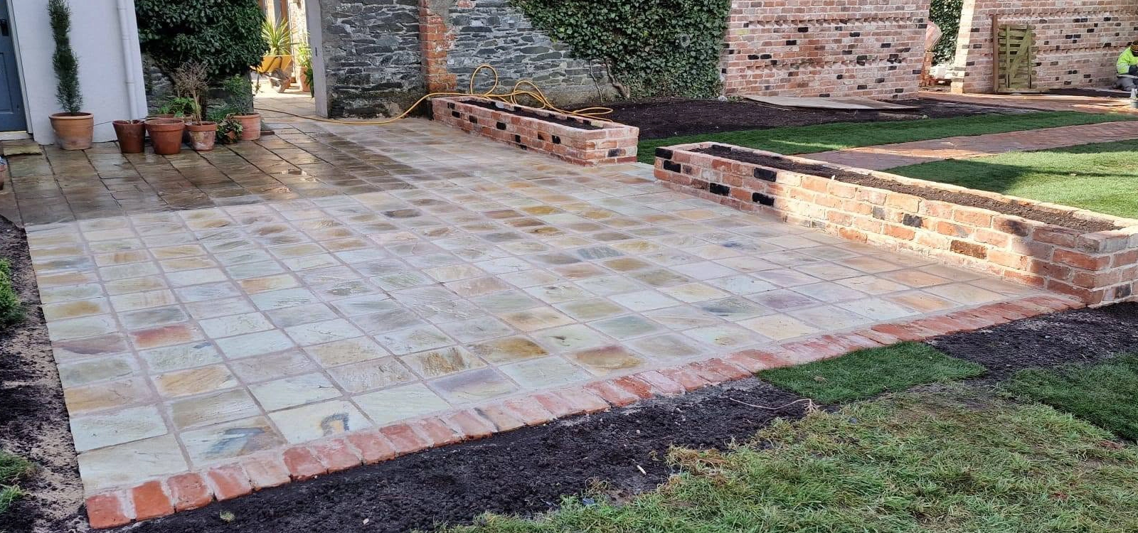 Paved patio with brick borders beside the lawn and garden wall