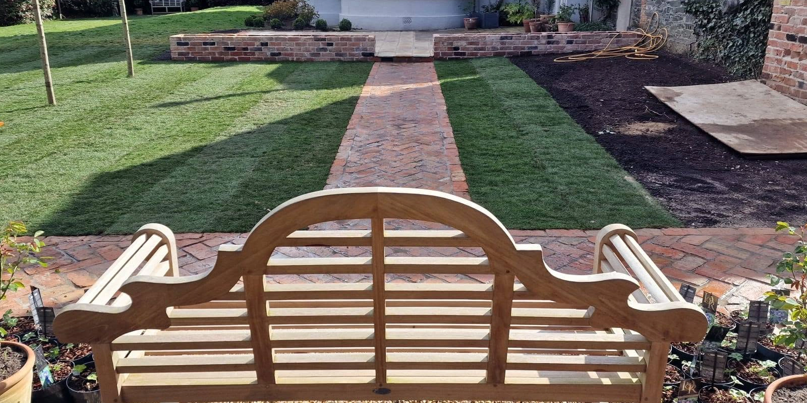 Garden path crossing the lawn towards a brick-edged planting area