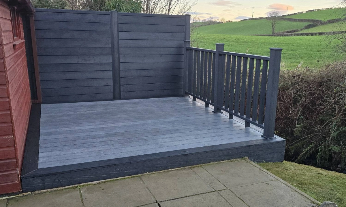 Garden decking beside a house with surrounding fencing and a gate