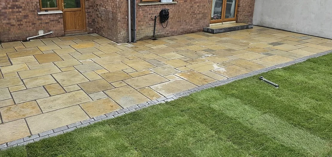 Paved patio beside a house and garden lawn